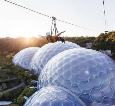 Person going down the zipwire at Eden at sunset with the biomes below
